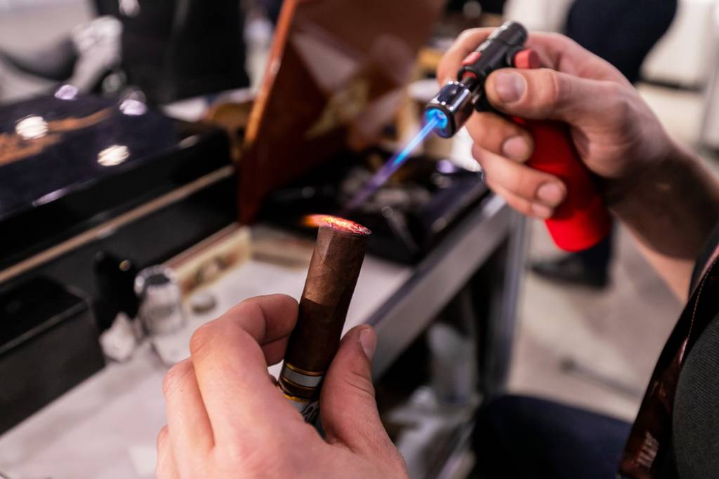 Man lights a cigar with a butane torch lighter