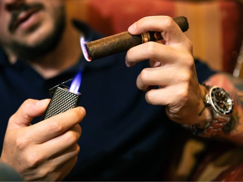 A cigar being lit by a torch lighter