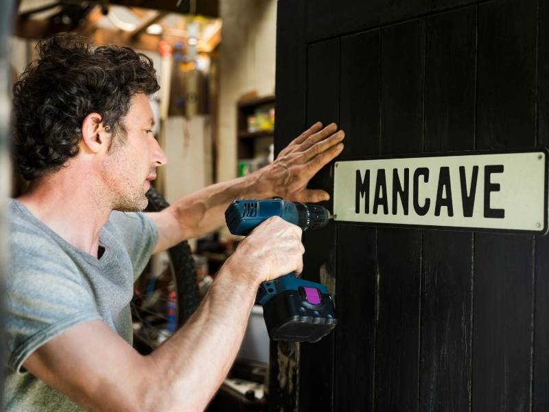 A man drilling a mancave sign on a door