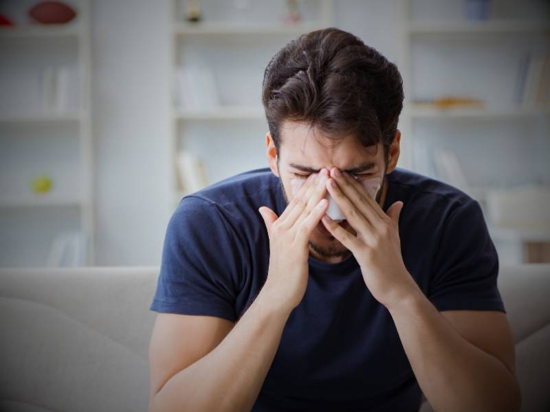 A man on a sofa with a stuffy nose