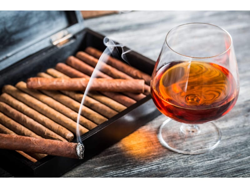 A box of cigars and a glass of alcohol used to illustrate how you would choose your cigar humidor