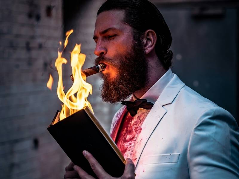 man lighting a cigar using a burning book