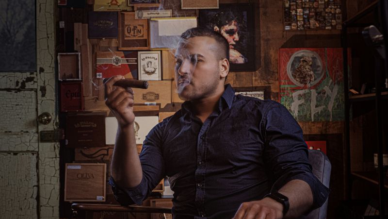 man sitting down and puffing a cigar